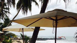 A beachside restaurant with outdoor seating, including tables and chairs under umbrellas, overlooking the ocean. - Coppenrath (Tangalle)