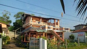 A two-story building with a balcony, a covered porch, and a gated entrance. - Coppenrath (Tangalle)