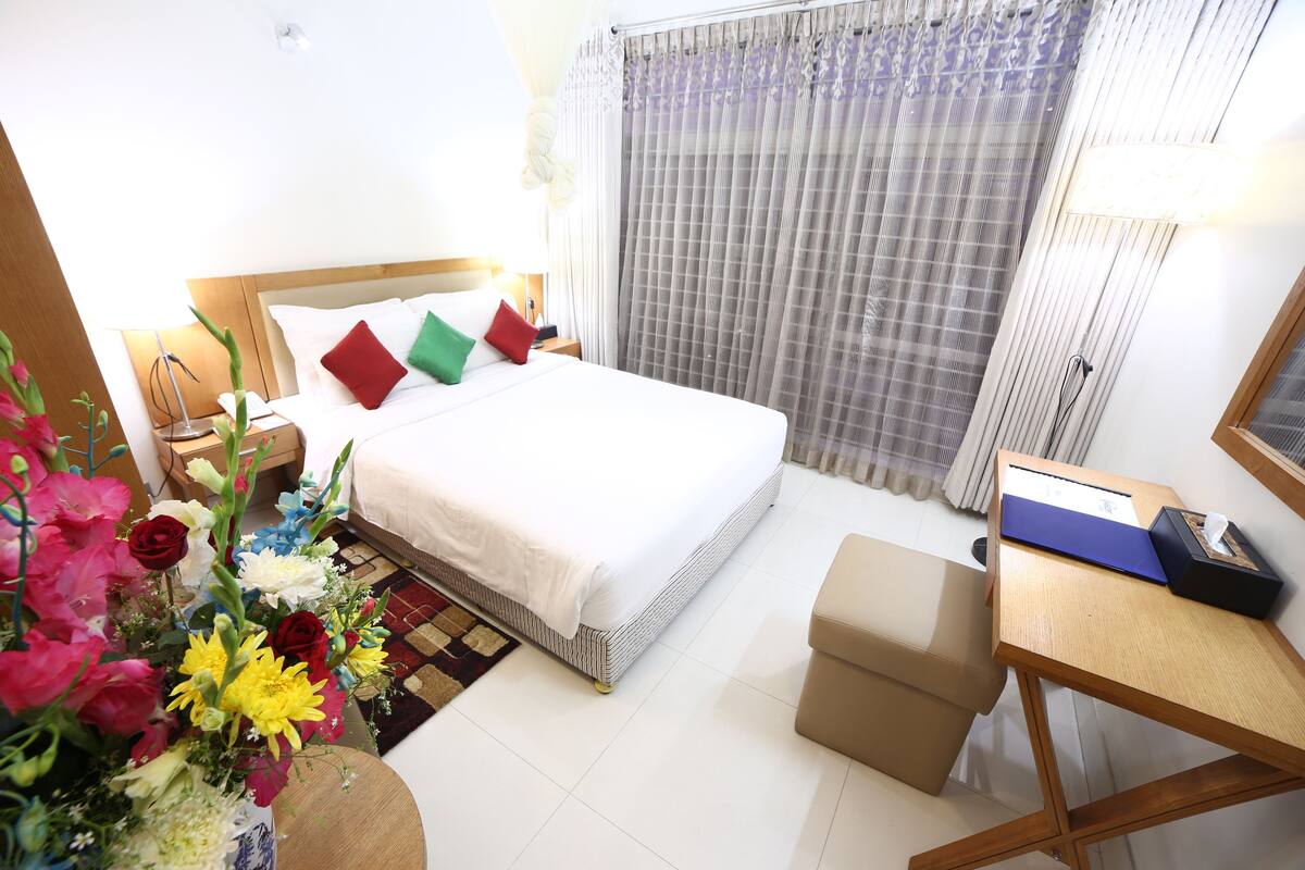 A hotel room with a bed, a desk, and a chair.