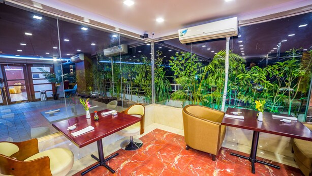 A modern indoor space with glass walls, red marble flooring, and green plants. - Nascent Gardenia Suites (Dhaka)