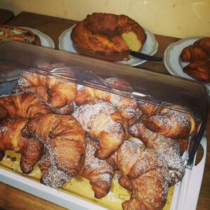 A display case filled with assorted pastries, including croissants and a bundt cake. - Osteria della Posta (Poggio Picenze)