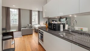A modern kitchen with a built-in oven, a sink, and a dining area with a table and chairs. - Destiny Scotland - St. Andrew Square Apartments (Edinburgh)