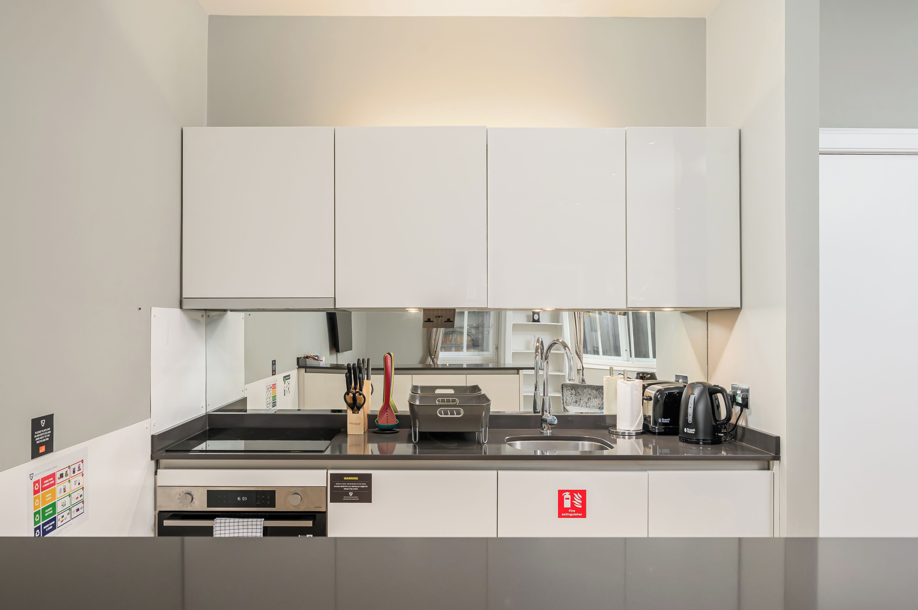 Una cucina moderna con mobili bianchi, un lavello in acciaio inossidabile e una macchina da caffè.