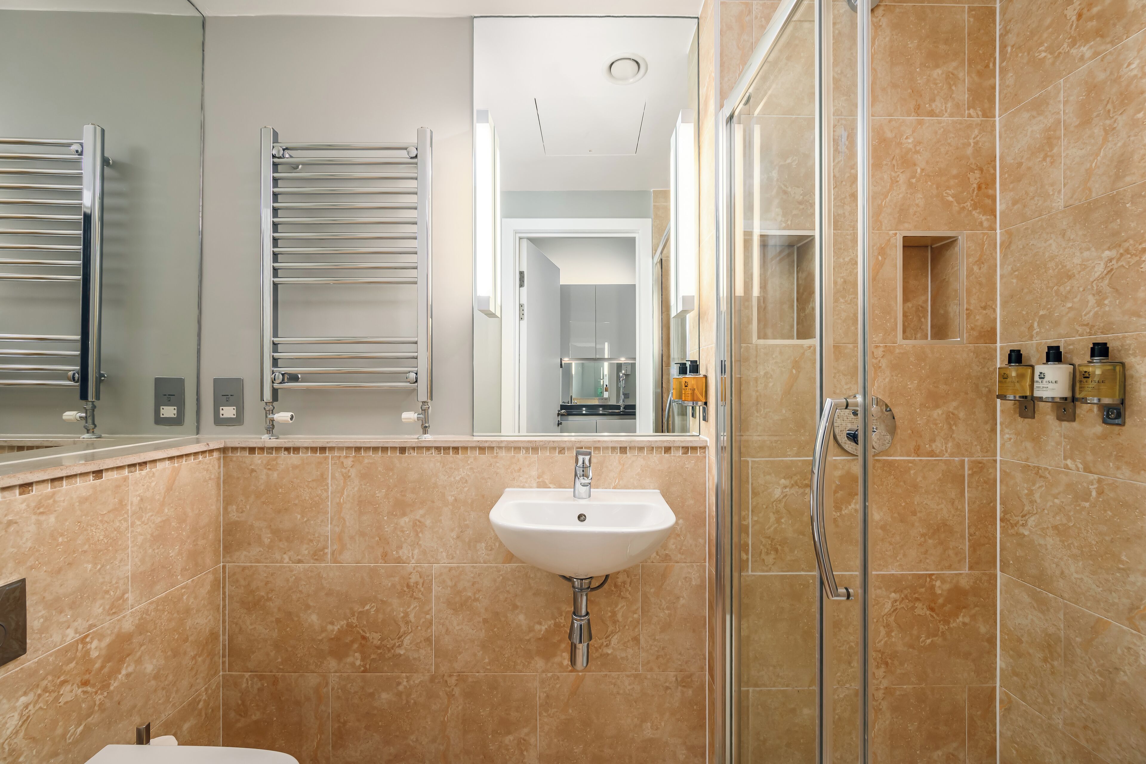 A modern bathroom with a sink, mirror, towel rack, shower, and toiletries.