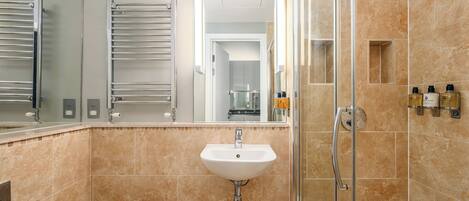 A modern bathroom with a sink, mirror, towel rack, shower, and toiletries.