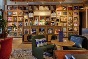 Et værelse med en reol fyldt med vinylplader, en grøn lænestol, et rundt træbord og en rød sofa.