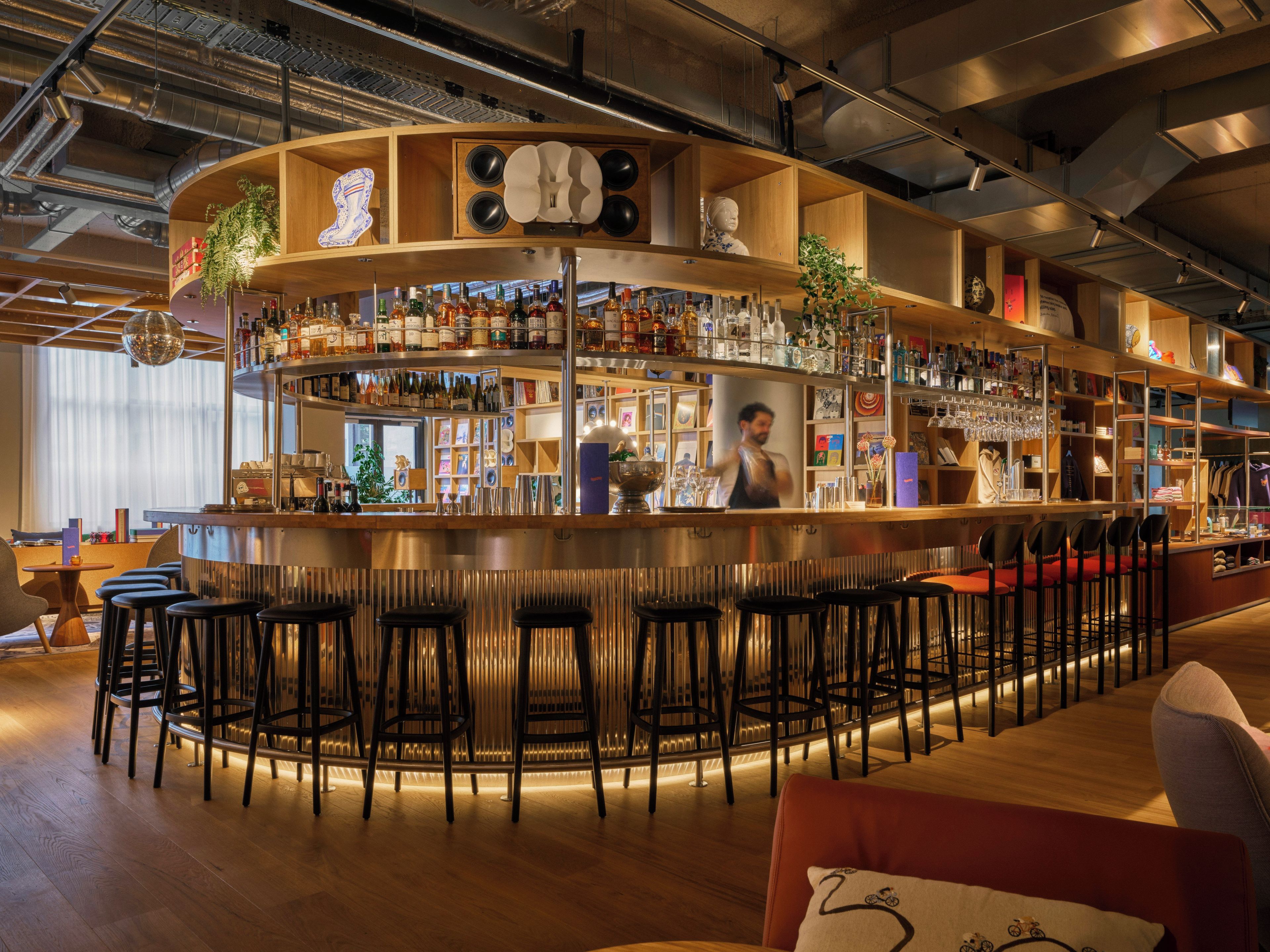 Eine Bar mit einer gebogenen Theke, mehreren Regalen mit Flaschen und Barhocker.