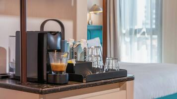 A hotel room's minibar with a coffee maker, a glass of coffee, and a bottle of water.