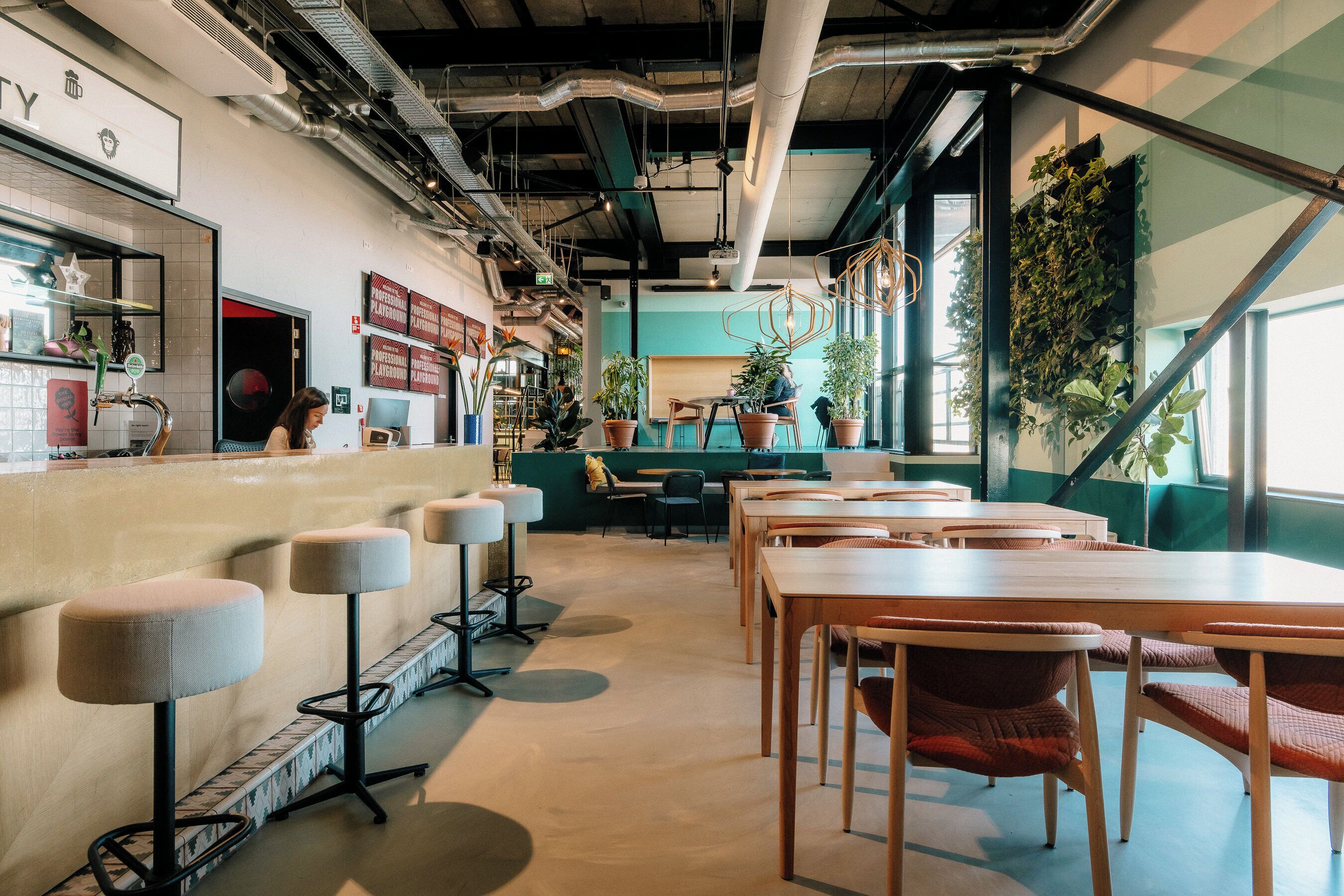 A modern interior with a bar area, seating, and plants.
