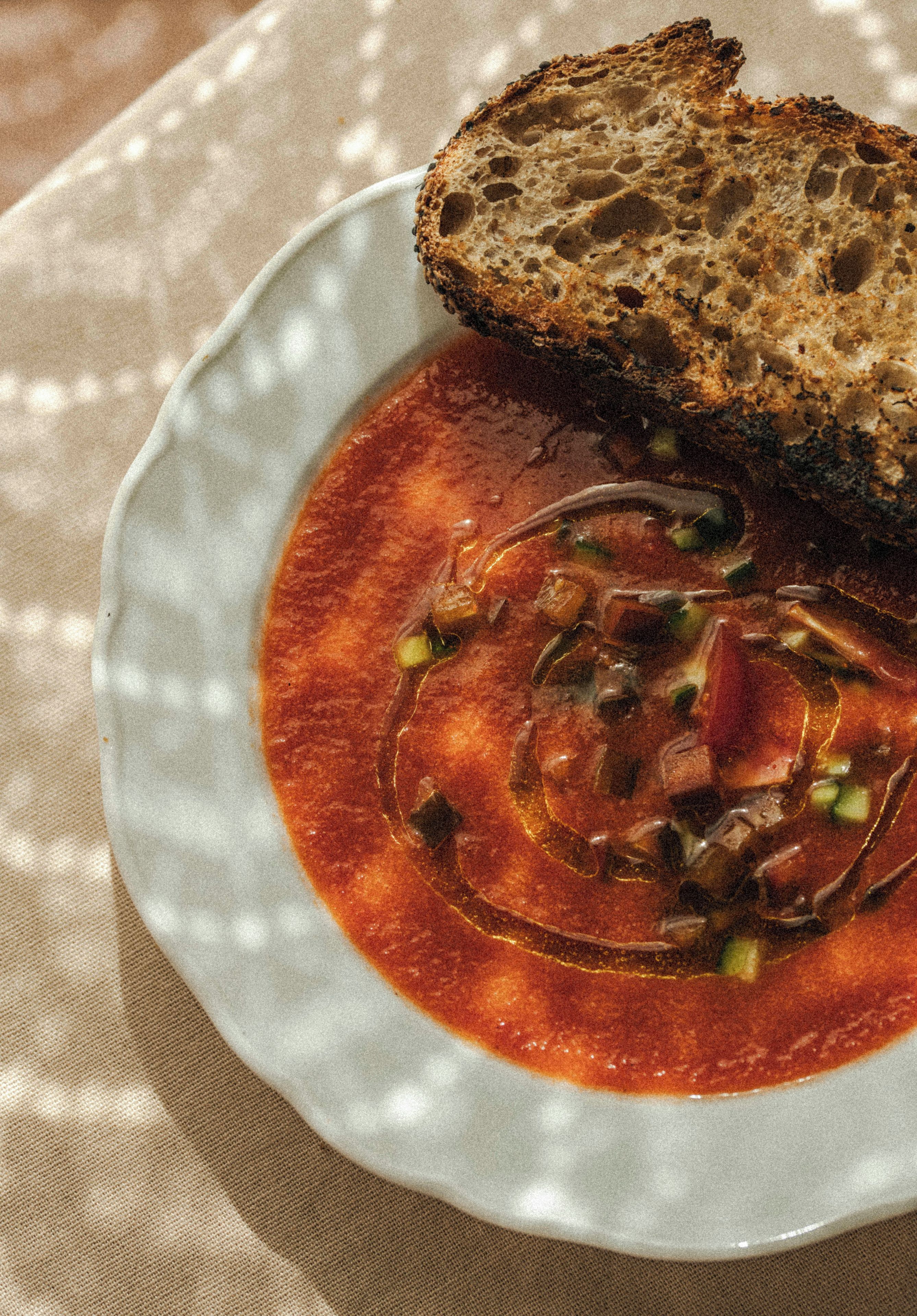 A bowl of soup with a slice of bread on a plate.