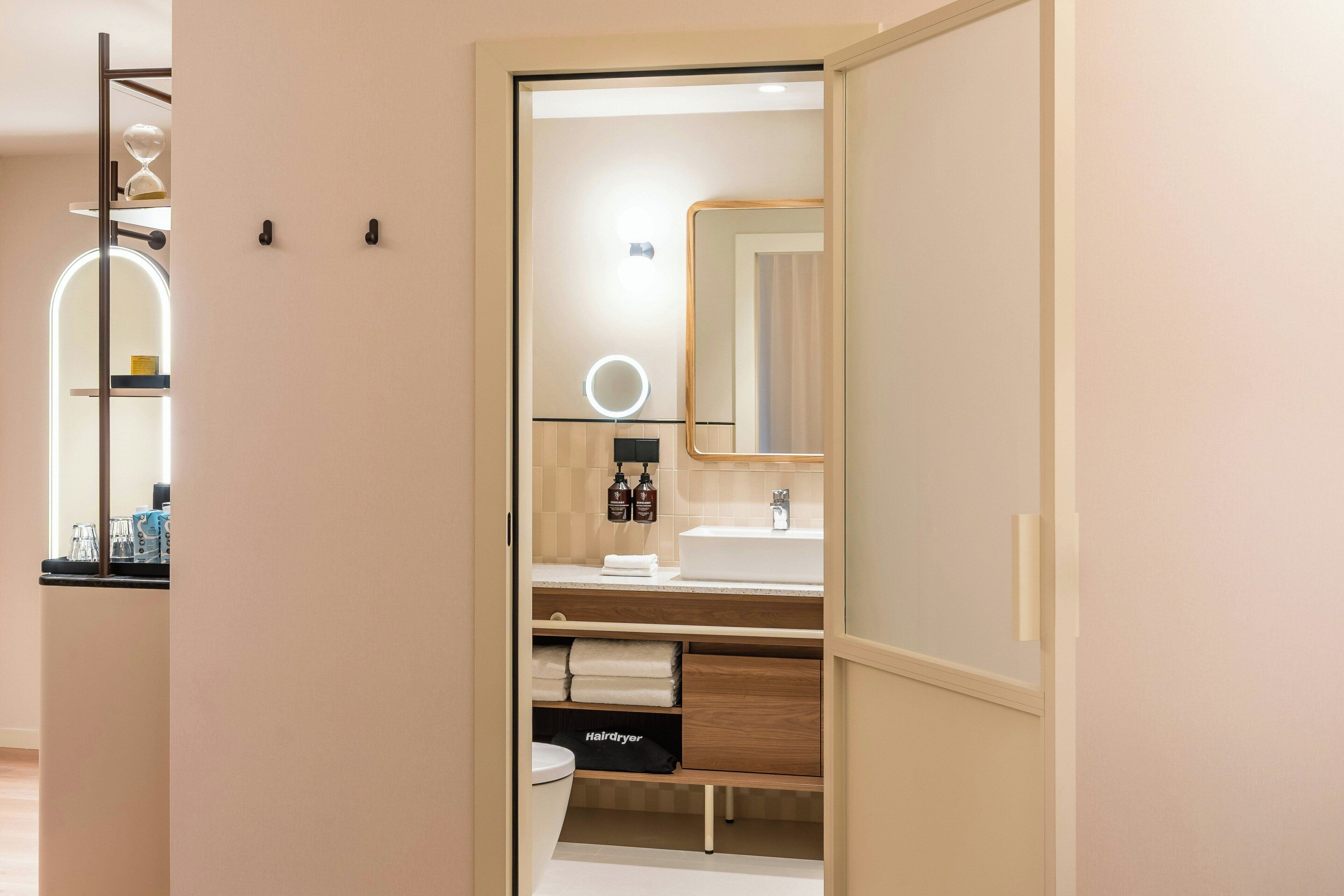 Ein modernes Badezimmer mit Waschtisch, Spiegel, Spüle und einem Fön.