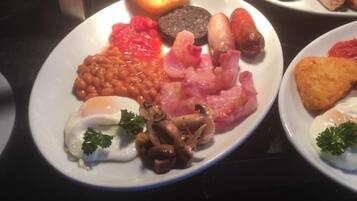 A breakfast buffet with various dishes including eggs, sausages, beans, and toast.