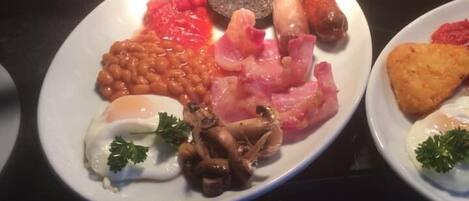 En morgenmadsbuffet med forskellige retter, heriblandt æg, pølser, bønner og ristet brød.
