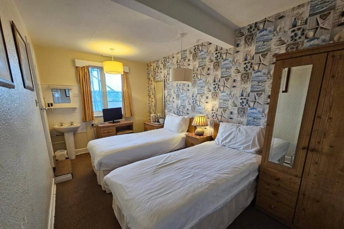 Een kamer met twee bedden, een bureau, een stoel, een spiegel en een kledingkast.