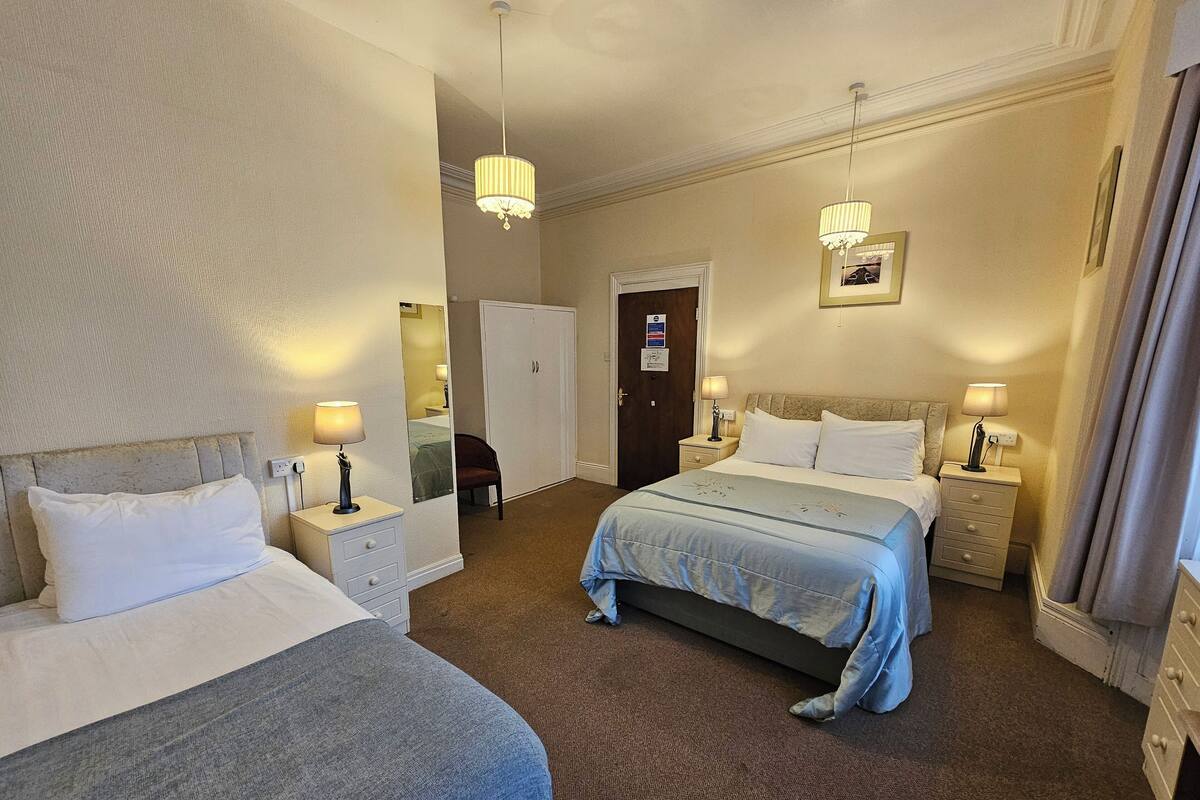 Een hotelkamer met twee bedden, een garderobe, een spiegel en twee bedlampjes.