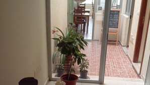 A hallway with potted plants, a glass door leading to a dining area, and a sign with a logo. - Tarrafal Residence (Tarrafal)