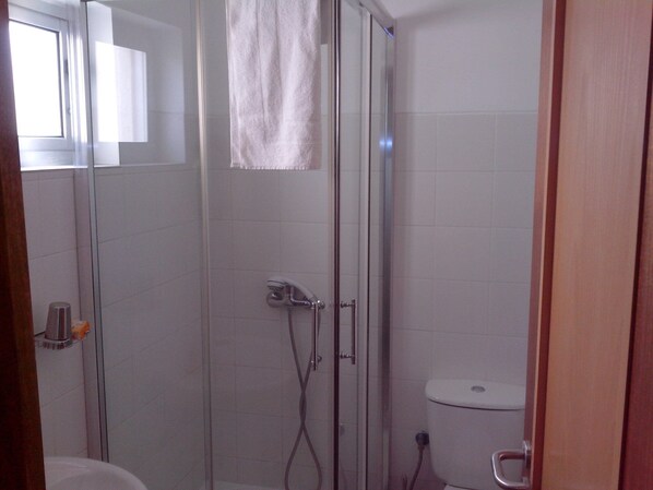 Un baño con ducha de mampara, inodoro y lavamanos.
