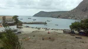 A coastal area with boats docked at a pier, a sandy beach, and a mountainous backdrop. - Tarrafal Residence (Tarrafal)
