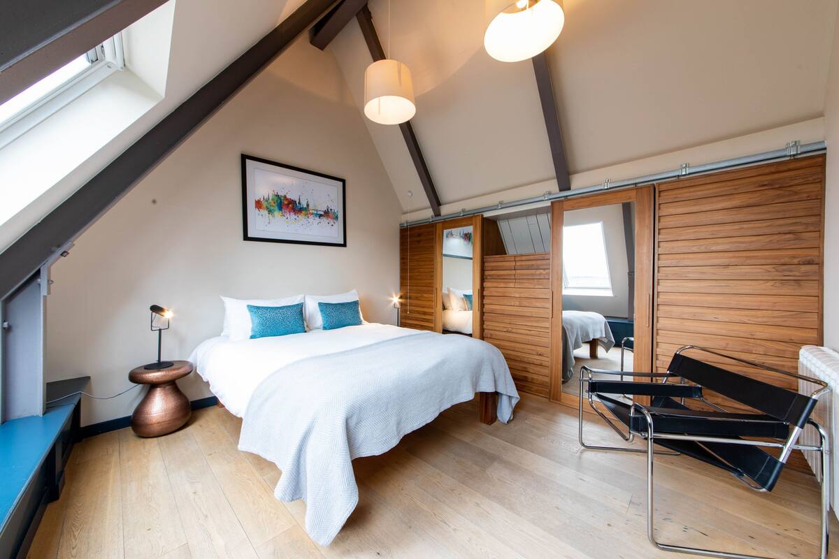 Une chambre avec un grand lit, un bureau, une chaise et une fenêtre.