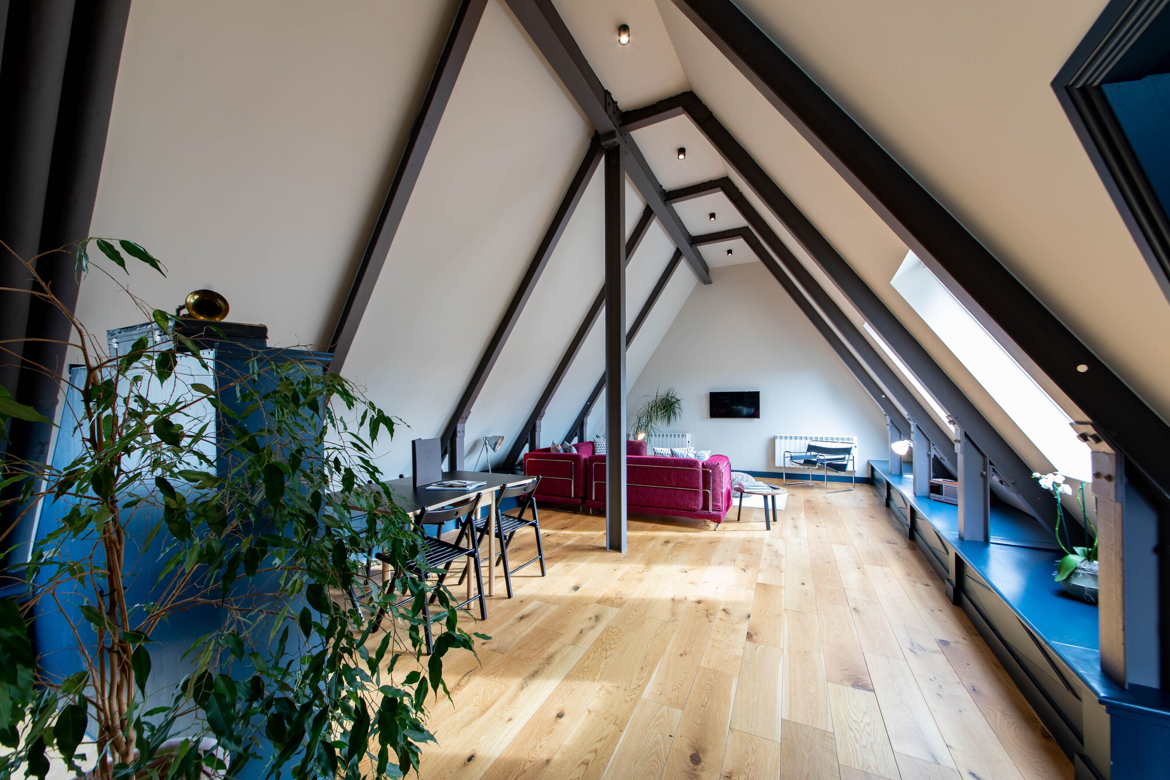 Un loft espacioso con techos altos, vigas a la vista y piso de madera.