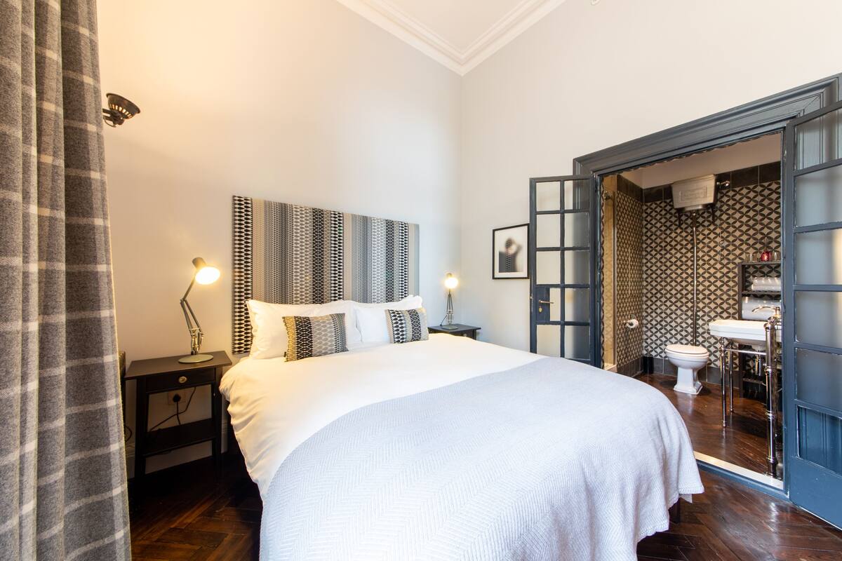 Un lit bien fait, avec une tête de lit, des lampes de chevet et une table de chevet.