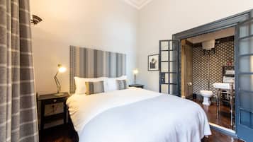 A neatly made bed with a headboard, bedside lamps, and a nightstand.
