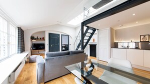 Un salon moderne avec un canapé gris, une table basse en verre et un escalier menant à un niveau supérieur.