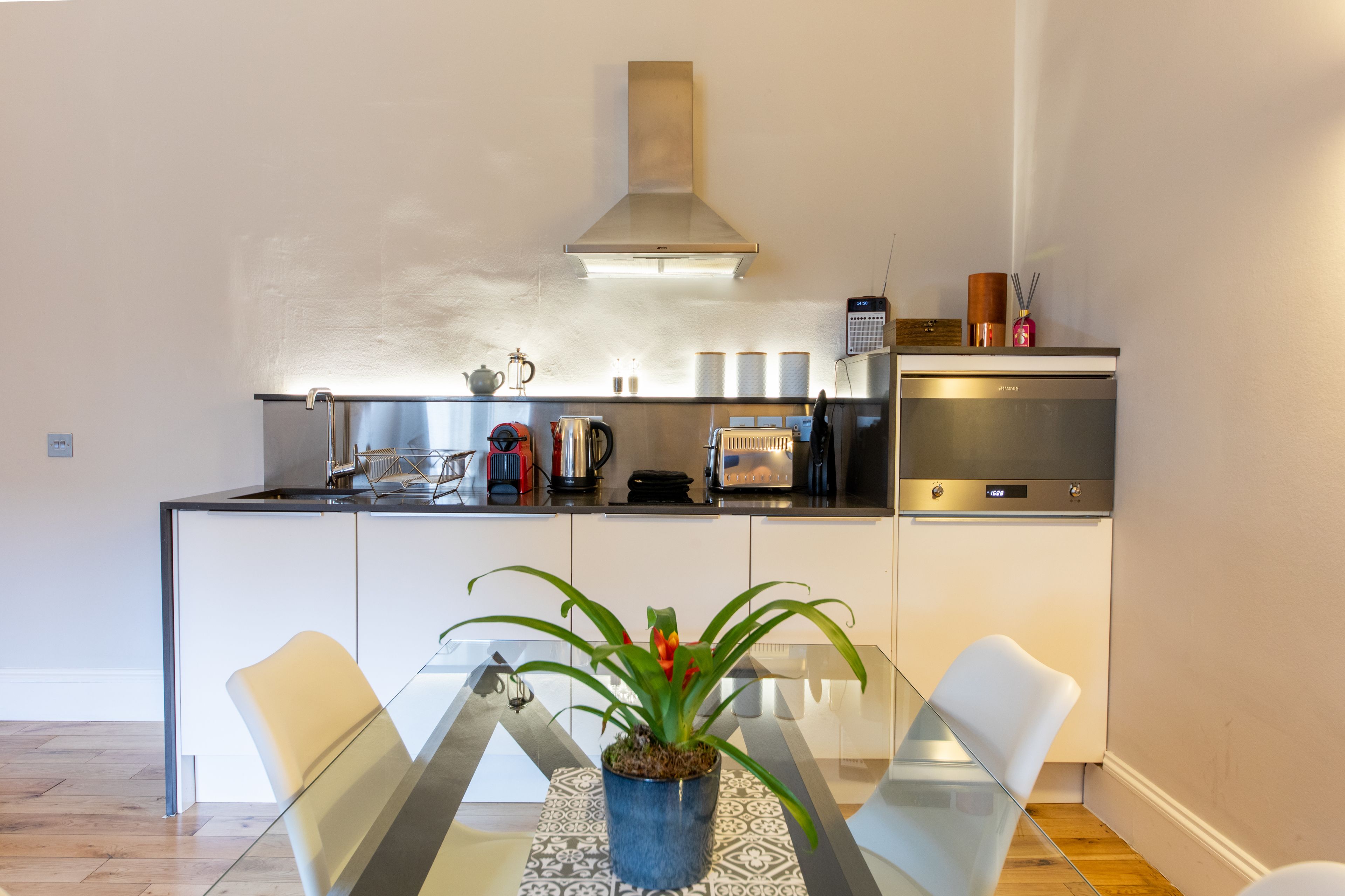 A modern kitchen with a central island, stainless steel appliances, and a dining area with a glass table and chairs.