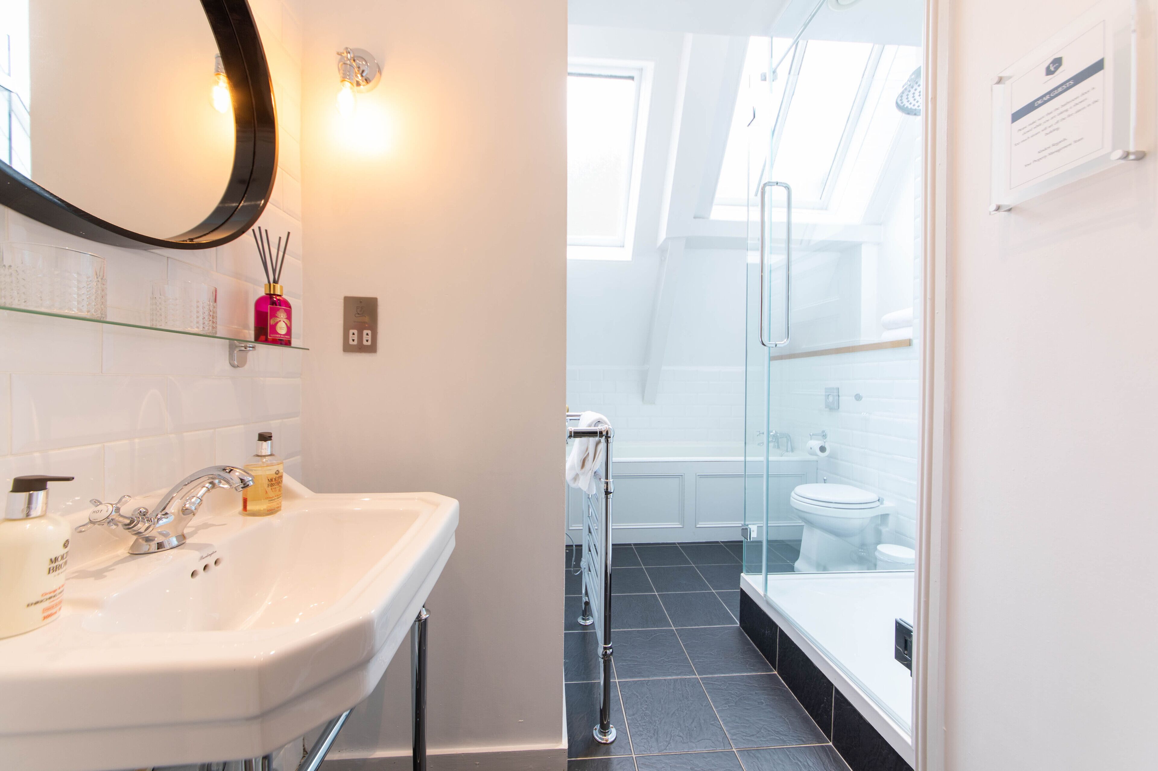 Een moderne badkamer met een wit wastafelmeubel, spiegel en douchecabine met glazen wanden.