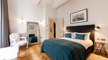 Une chambre à coucher avec un grand lit, une chaise, un miroir et un tableau encadré au mur.