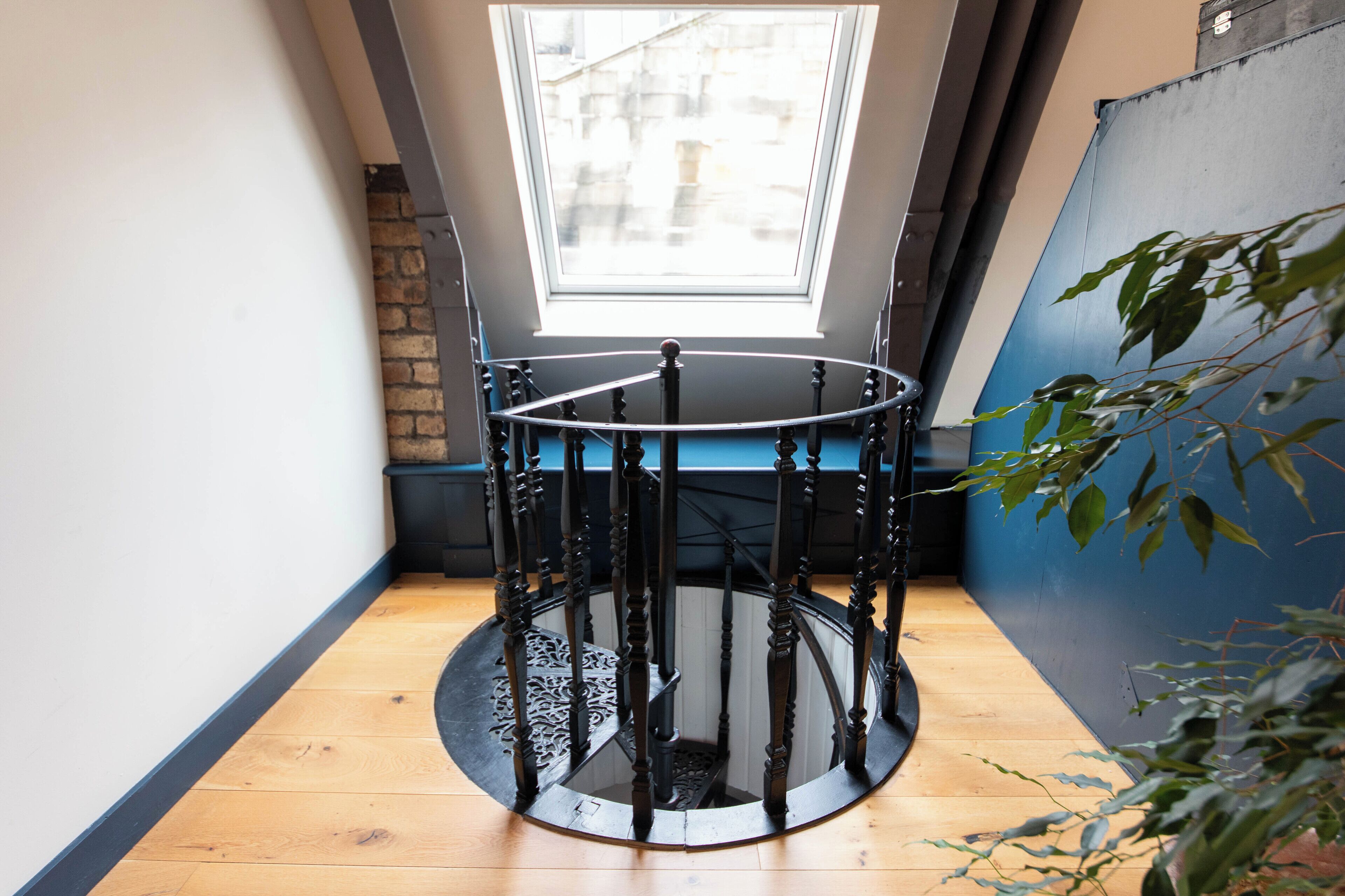 A circular table with a black metal frame, a wooden floor, and a view of a building through a skylight.