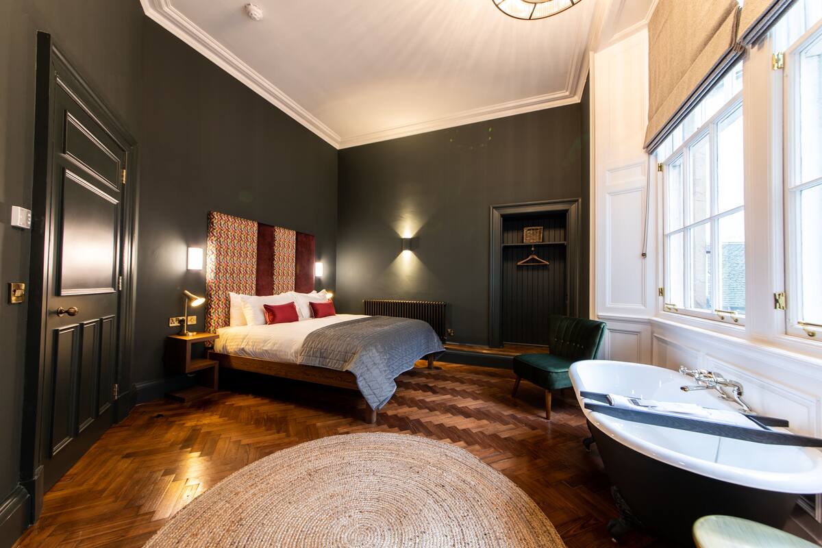 Une chambre dotée d’un grand lit, d’un coin salon et d’une baignoire.