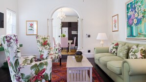 Een woonkamer met een bank, stoelen, een salontafel en een schilderij.