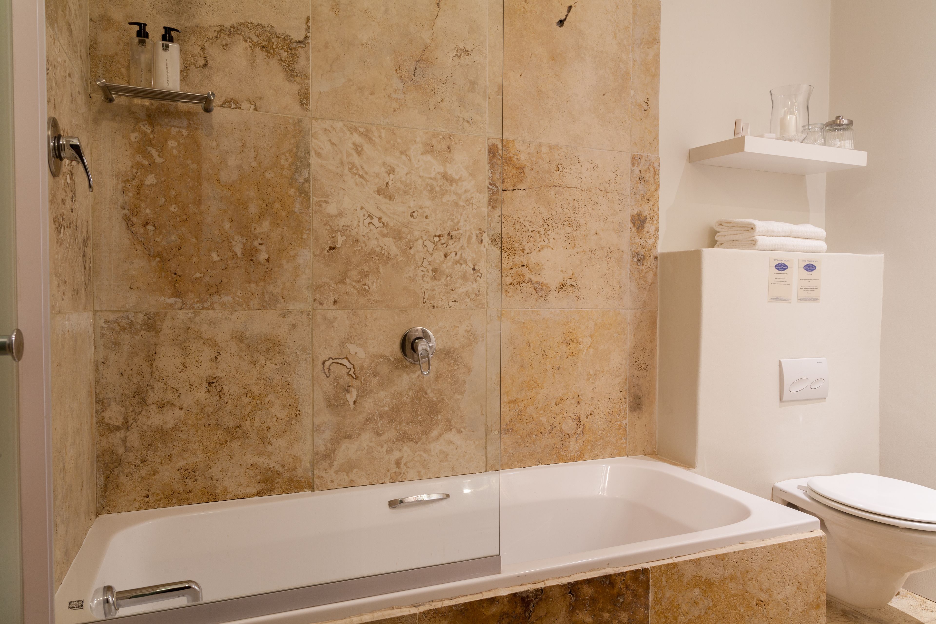 Een badkamer met een bad, een toilet en een plank met toiletartikelen.