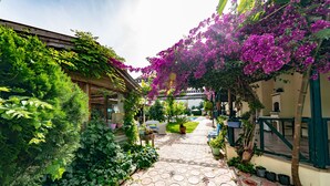 A garden pathway with a tiled floor, surrounded by lush greenery and flowering plants. - Dedeminn Garden Hotel (Fethiye)