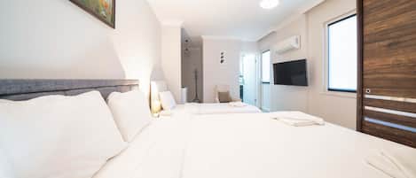 A hotel room with a large bed, a TV, a wooden wardrobe, and a painting on the wall.