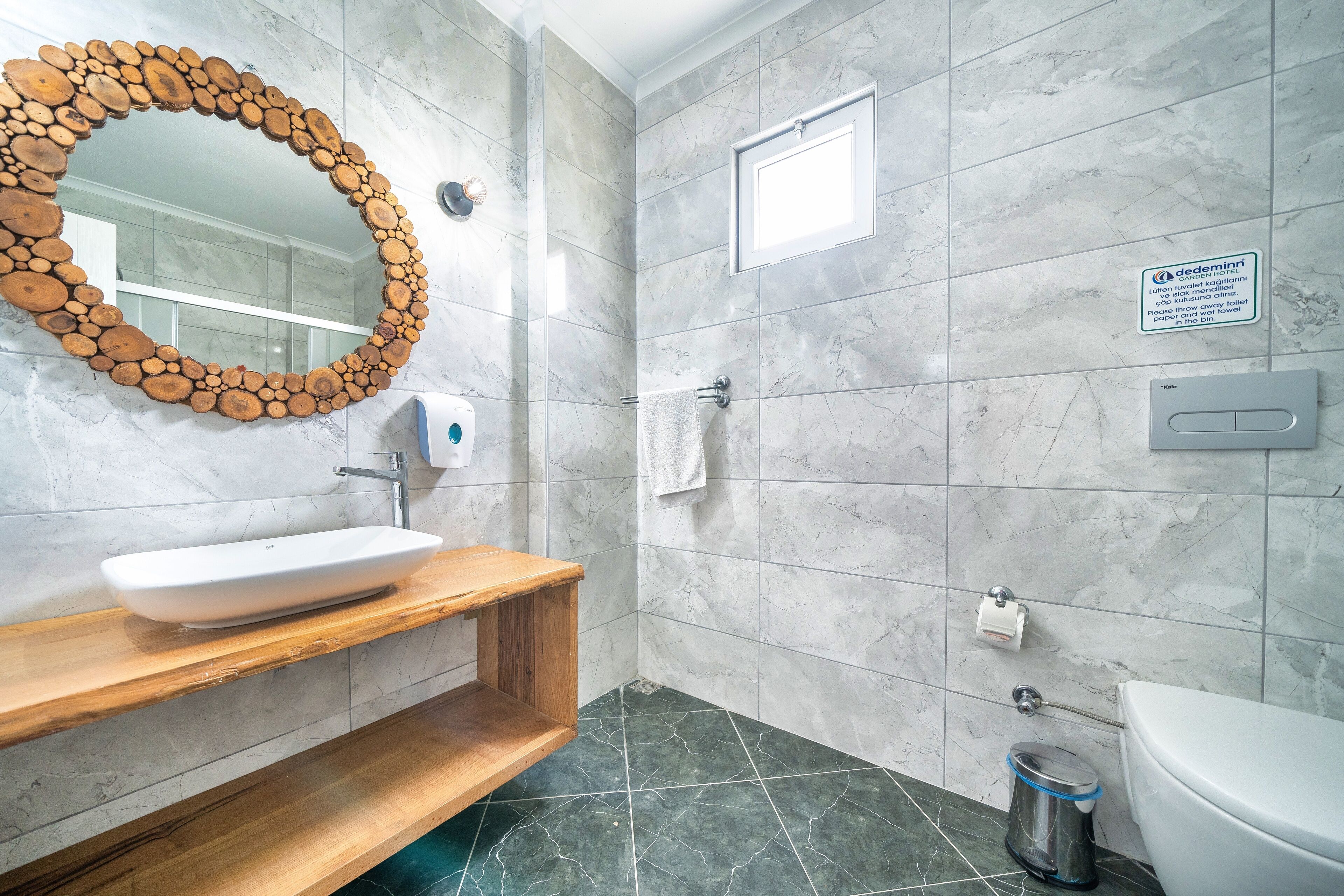 A modern bathroom with a wooden-framed mirror, a white sink, and a toilet.