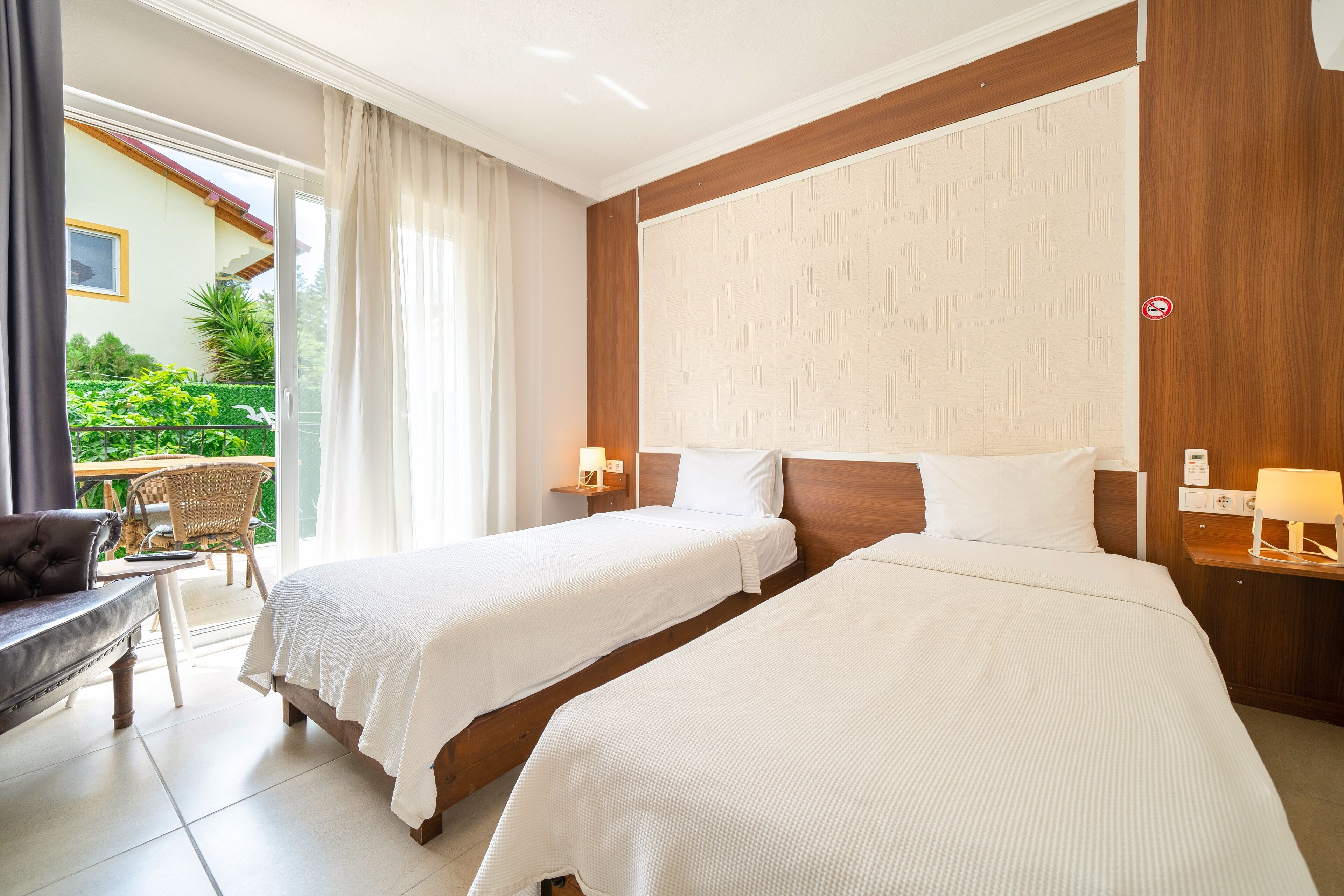 Une chambre d’hôtel avec deux lits, un canapé, une petite table et vue sur le jardin.