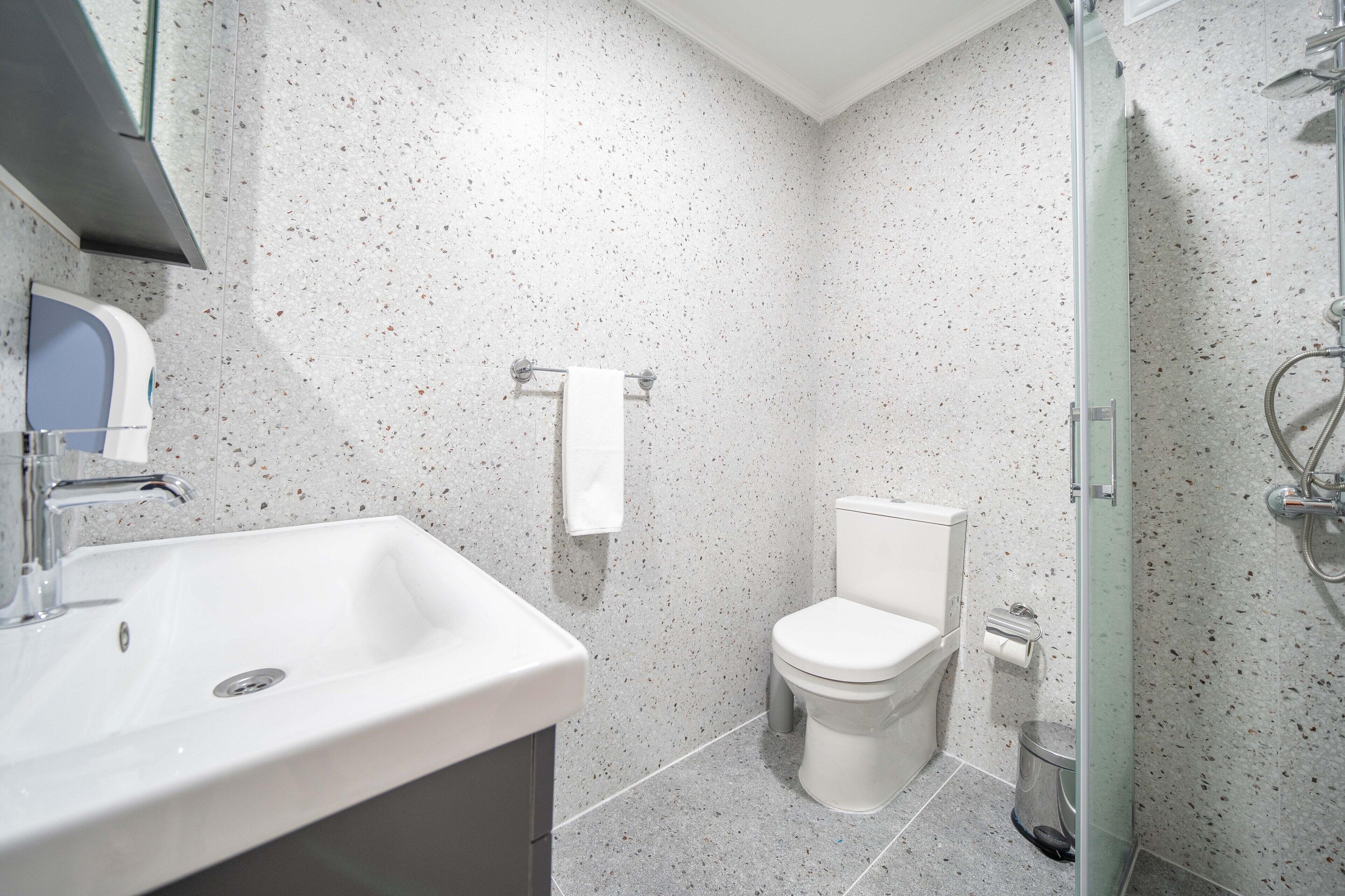 A modern bathroom with a white sink, toilet, and shower.