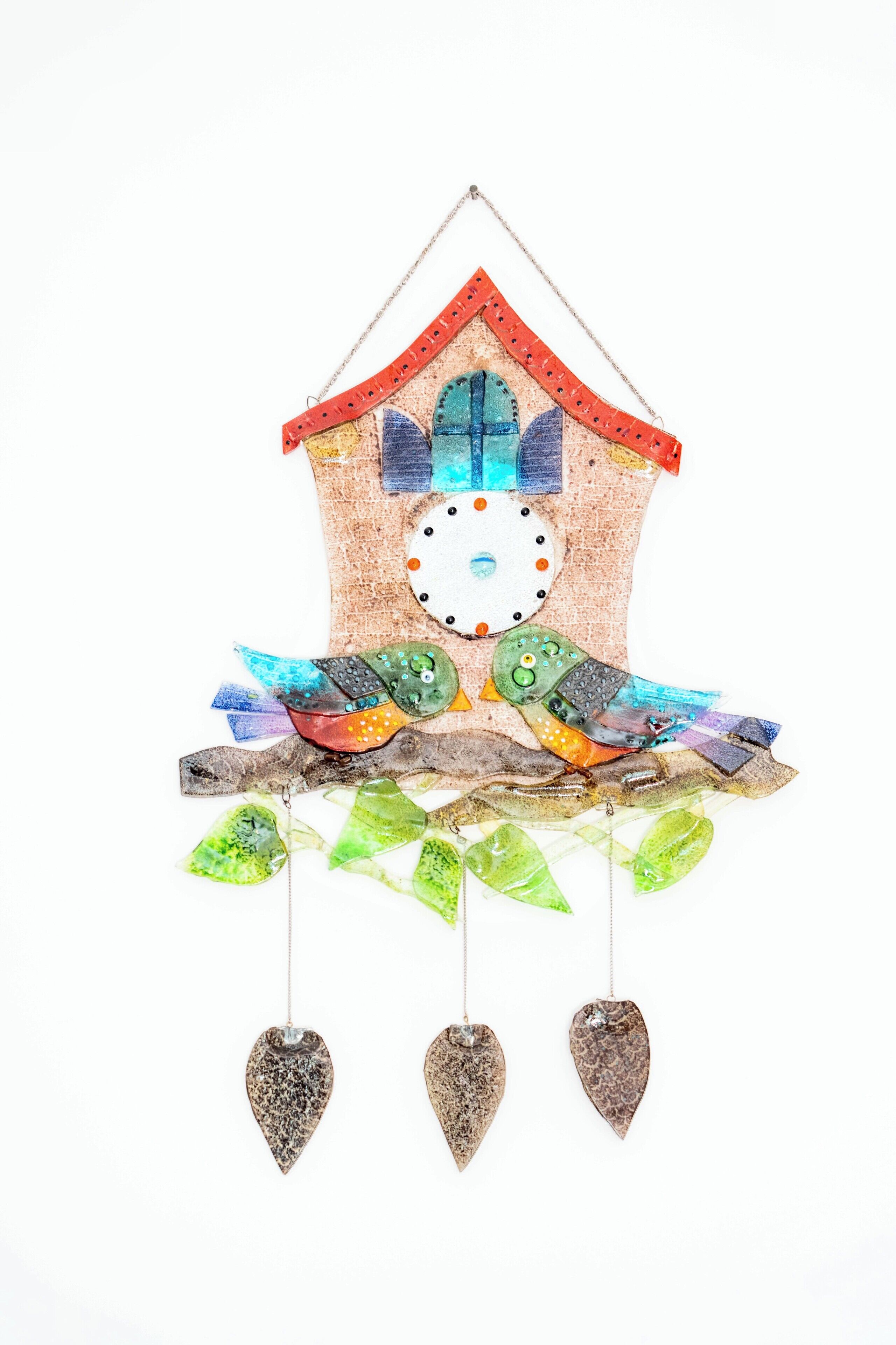 Un móvil decorativo con forma de casa en la parte superior y hojas colgantes.