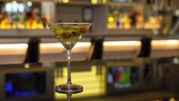 A martini glass with olives on a bar counter.
