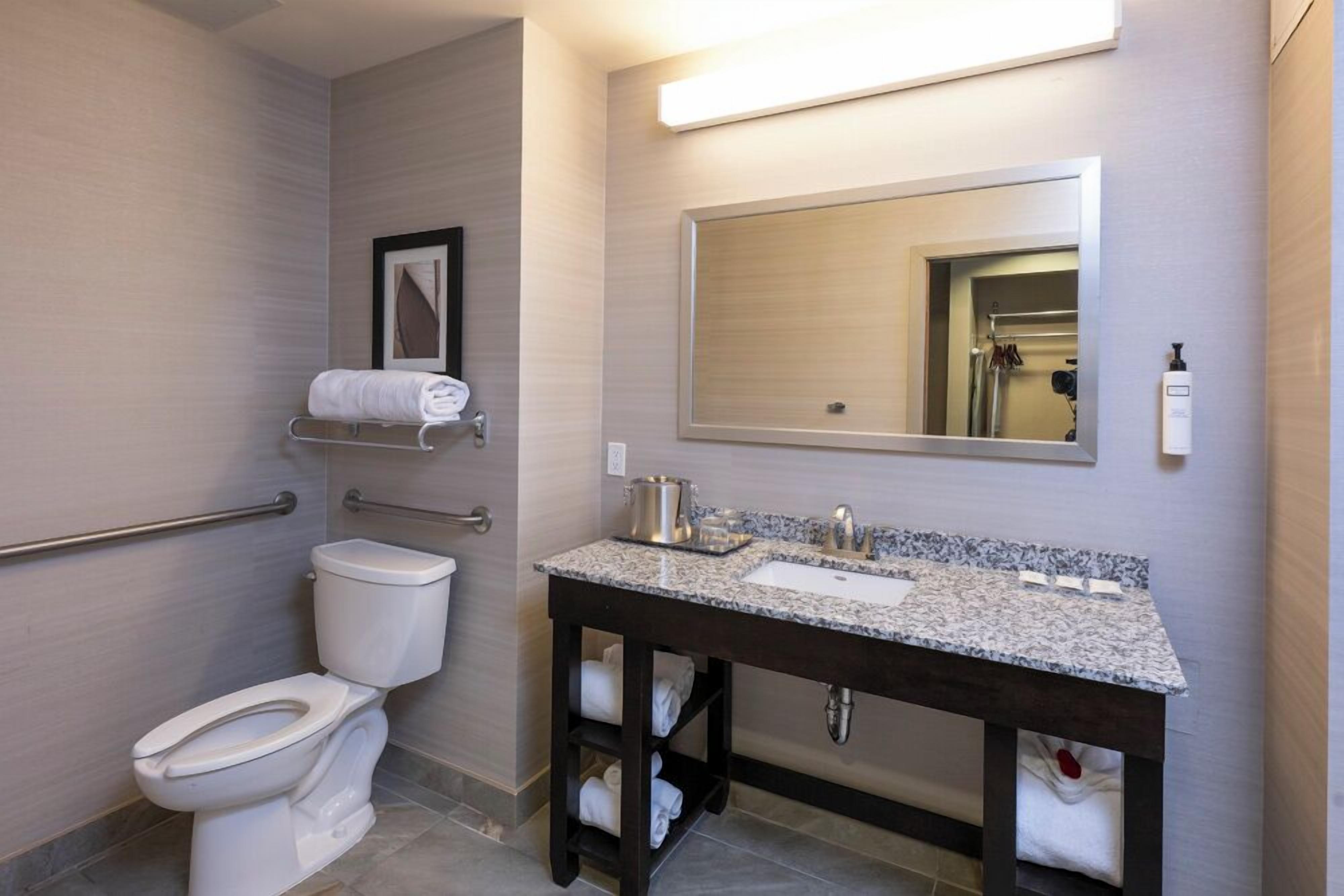 Un bany amb vàter, un lavabo amb mirall i una barra de tovalloles.