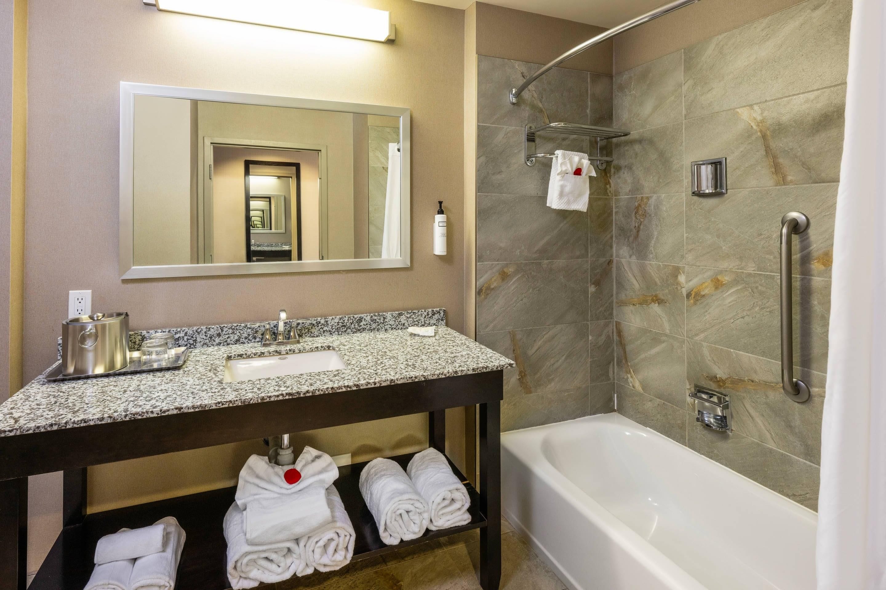 A bathroom with a sink, mirror, towel rack, shower, and bathtub.