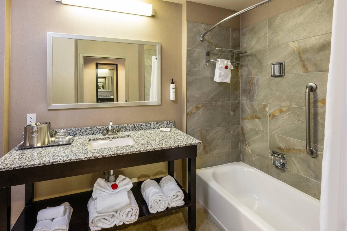 A bathroom with a sink, mirror, towel rack, shower, and bathtub.