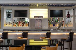 A bar area with multiple liquor bottles, two TVs, and a 'Gather Together' sign.