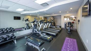 Un gimnasio con cintas de correr, mancuernas y un banco.