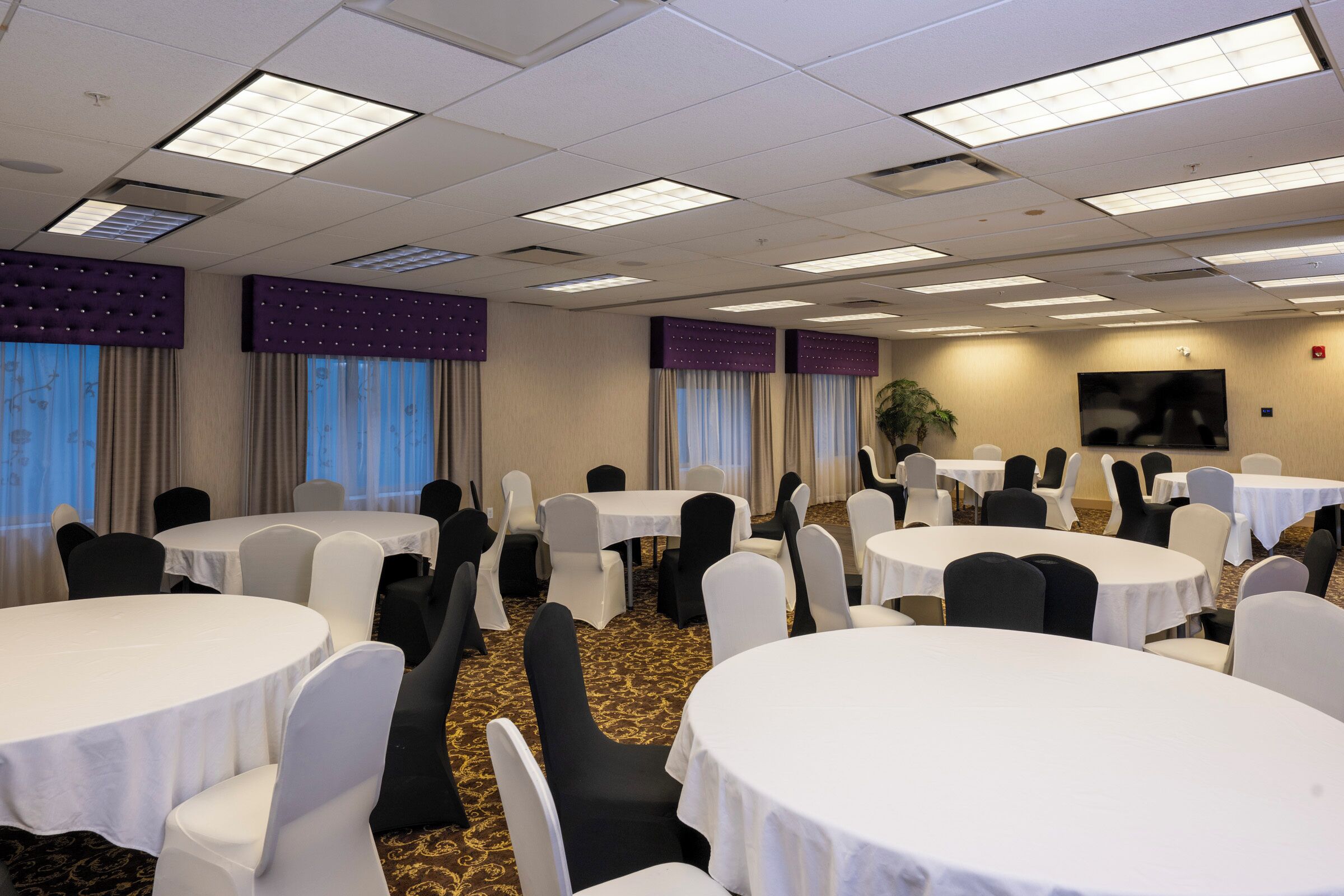Un salón de conferencias con varias mesas redondas, sillas y una pantalla grande.