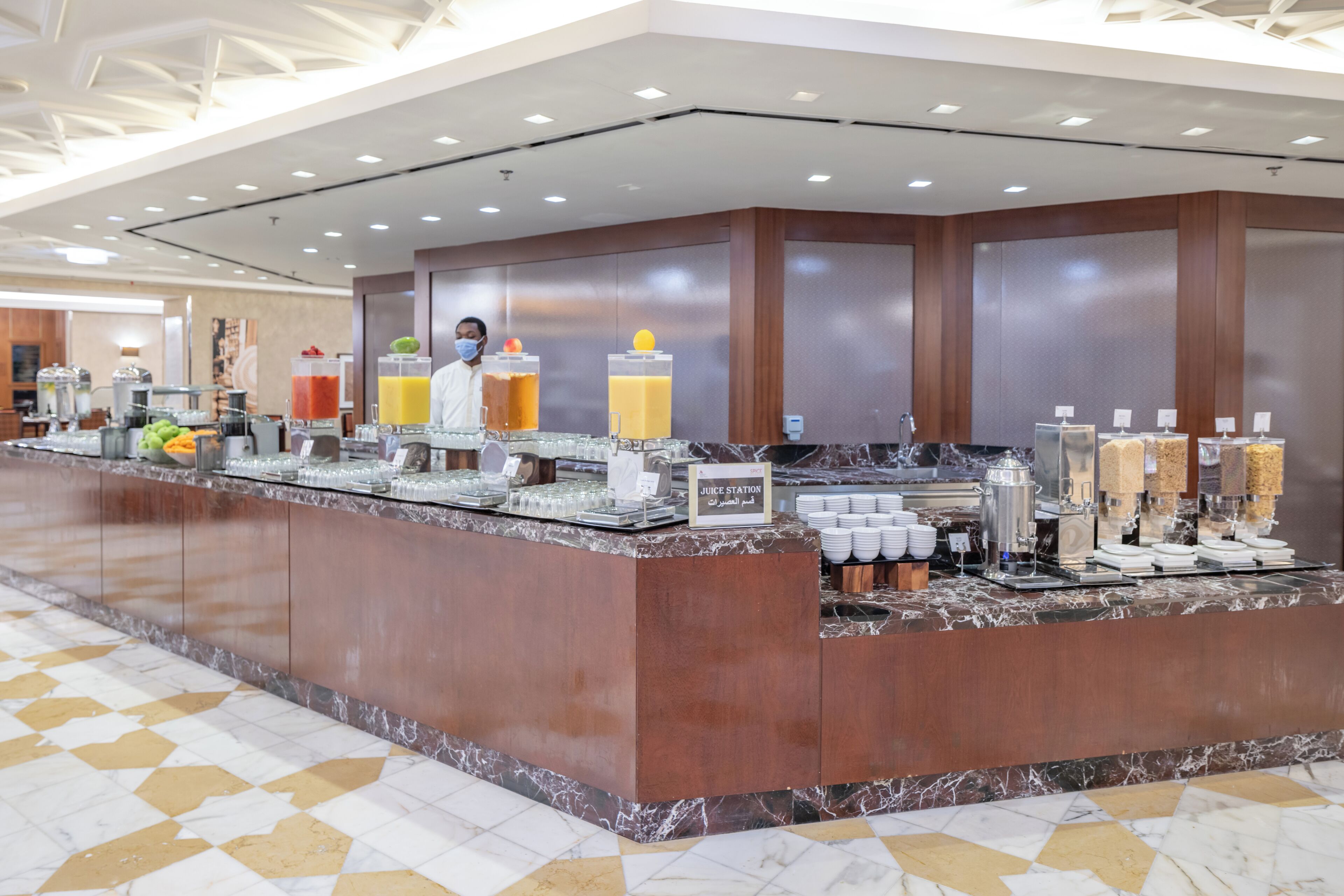 A buffet area with a marble counter, juice station, and various food and drink dispensers.
