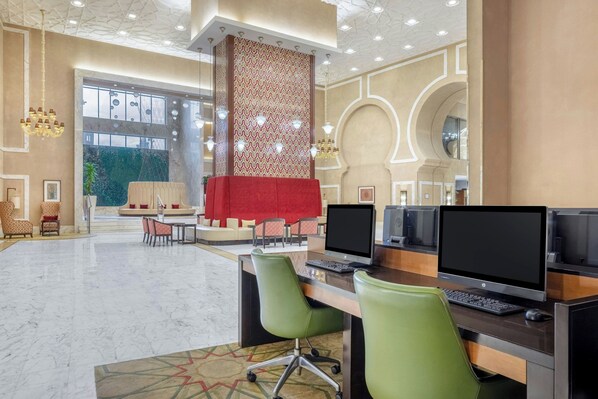 A modern hotel lobby with a reception desk, computers, and seating areas.