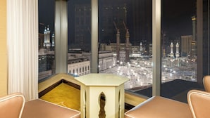 A high-rise hotel room with a view of a cityscape at night, including illuminated buildings and a mosque.